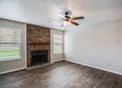 Thumbnail 13 of 27 - Living Room with Fireplace and Ceiling Fan at Bookstone and Terrace Apartments in Irving, Texas