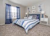 Thumbnail 13 of 37 - Model apartment bedroom with bed and blue curtains at The Oasis apartments in Bossier City, LA