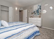 Thumbnail 14 of 37 - Model bedroom with a bed, dresser, and artwork on the wall at The Oasis apartments in Bossier City, LA