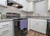 Thumbnail 8 of 37 - A kitchen with a black oven and white cabinets in our model at The Oasis apartments in Bossier City, LA