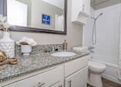 Thumbnail 15 of 37 - A bathroom with a sink, toilet, and a mirror at The Oasis apartments in Bossier City, LA