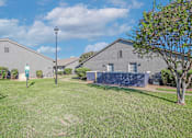 Thumbnail 29 of 37 - A grassy area in front of a building with a pet waste station at The Oasis apartments in Bossier City, LA