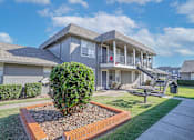 Thumbnail 3 of 37 - Apartment building with picnic table in front and lush greenery at The Oasis apartments in Bossier City, LA