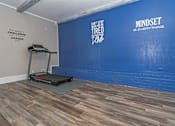 Thumbnail 23 of 37 - A treadmill is on a grey mat in a room with a blue wall at The Oasis apartments in Bossier City, LA