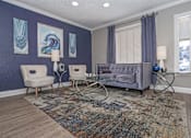Thumbnail 21 of 37 - Interior of leasing office with a grey couch, two chairs, and a rug at The Oasis apartments in Bossier City, LA