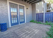 Thumbnail 16 of 37 - Model apartment concrete patio with a blue trash can and a blue fence at The Oasis apartments in Bossier City, LA