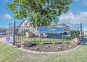 Thumbnail 37 of 37 - A sign for The Oasis with Apartments, Cottages, Townhomes is displayed in front of a fence at The Oasis apartments in Bossier City, LA