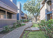 Thumbnail 2 of 23 - Walkways in between apartments with lush landscaping at The Pearl apartments in Shreveport, LA