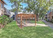Thumbnail 19 of 23 - A backyard with a swing set and a wooden pergola.
