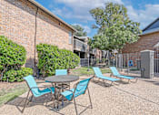 Thumbnail 12 of 23 - A pool area with a table and chairs is surrounded by brick apartment buildings at The Pearl apartments in Shreveport LA