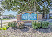 Thumbnail 23 of 23 - A sign for The Pearl Apartment Homes stands in front of a tree.