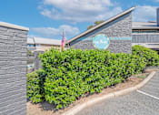 Thumbnail 22 of 23 - A building with a sign that says "The Pearl" is surrounded by green bushes.
