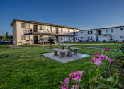 Thumbnail 5 of 25 - A building with a balcony and a patio table surrounded by flowers.