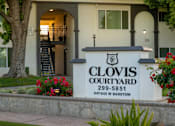 Thumbnail 1 of 25 - The entrance to Clovis Courtyard with a sign and flowers.