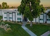Thumbnail 4 of 25 - A white building with a tree in front of it.