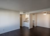 Thumbnail 22 of 25 - A room with a ceiling fan and a kitchen area in the background.