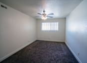 Thumbnail 16 of 25 - A room with a ceiling fan and carpeted floor.