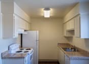 Thumbnail 14 of 25 - A small kitchen with a white stove and a refrigerator.