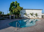 Thumbnail 10 of 25 - A pool with a diving board in front of a white building.