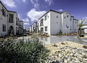 Thumbnail 1 of 18 - a row of white houses with gravel and trees
