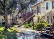 Thumbnail 6 of 32 - a walkway in front of an apartment building with stairs and trees