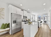 Thumbnail 2 of 13 - A modern kitchen with a stainless steel refrigerator and white cabinets.