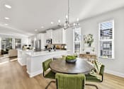 Thumbnail 5 of 13 - A modern kitchen with a dining table and chairs.