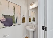 Thumbnail 13 of 13 - A bathroom with a white sink and a painting on the wall.