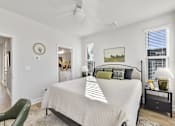 Thumbnail 10 of 13 - A bedroom with a large bed, a green chair, and a painting on the wall.