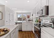 Thumbnail 2 of 12 - A kitchen with white cabinets and a wooden island.
