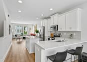 Thumbnail 4 of 16 - A modern kitchen with white cabinets and a large island.