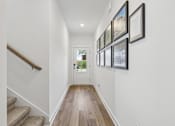Thumbnail 5 of 49 - A hallway with a staircase and pictures on the wall.