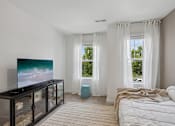 Thumbnail 10 of 49 - A modern bedroom with a large bed and a television.