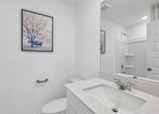 Thumbnail 13 of 49 - A bathroom with a white sink and a framed picture of a tree on the wall.