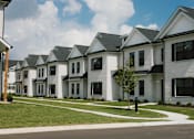 Thumbnail 1 of 17 - A row of white houses with black shutters and grey roofs.