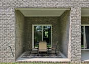 Thumbnail 15 of 49 - A patio with a table and chairs is framed by a brick wall.