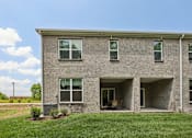 Thumbnail 16 of 49 - A grey brick house with a green lawn in front.