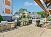 Thumbnail 14 of 16 - A sunny day at a residential complex with a blue car parked in front of a white building.