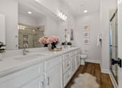 Thumbnail 10 of 12 - A bathroom with a white vanity and a mirror above it.