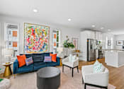 Thumbnail 6 of 16 - A living room with a blue couch and a large painting on the wall.