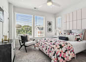 Thumbnail 6 of 12 - A bedroom with a bed, chair, and window.