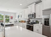 Thumbnail 5 of 12 - A modern kitchen with white cabinets and stainless steel appliances.