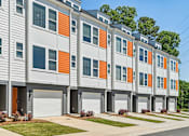 Thumbnail 1 of 12 - A row of modern townhouses with orange and grey accents.