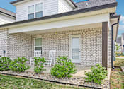 Thumbnail 2 of 24 - A house with a white porch and a grey roof.