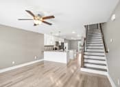 Thumbnail 3 of 24 - A spacious living room with a staircase leading to the upper floor.