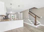Thumbnail 5 of 24 - A modern kitchen with a marble countertop and a staircase with a wooden handrail.
