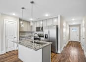 Thumbnail 6 of 24 - A modern kitchen with a granite countertop and stainless steel appliances.