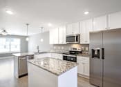 Thumbnail 7 of 24 - A modern kitchen with granite countertops and stainless steel appliances.