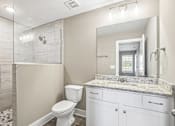 Thumbnail 11 of 24 - A bathroom with a marble countertop and a walk-in shower.
