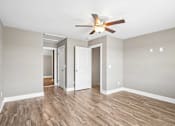 Thumbnail 13 of 24 - A room with a ceiling fan and wooden floors.
